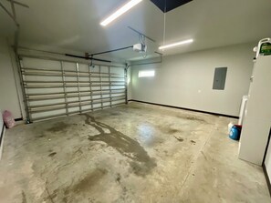 Ett garage med ett betonggolv, en stängd metallport och en projektor som är monterad i taket.