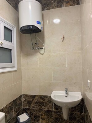 A bathroom with a white pedestal sink, a toilet, and a wall-mounted heater. - La Prestigia 2BR With a big Balcony (Hurghada)
