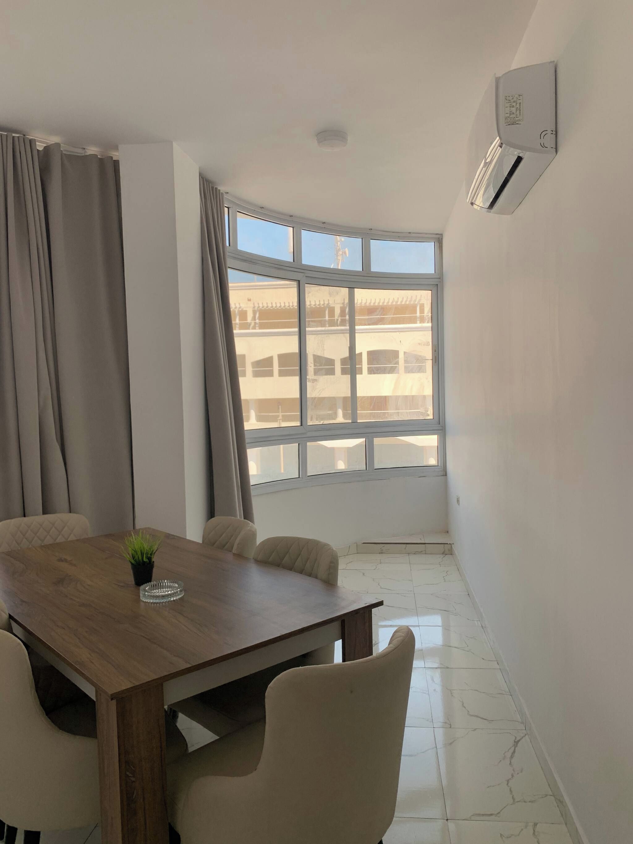 A modern room with a large window, a wooden table, and four chairs.