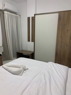 A hotel room with a bed, a wooden nightstand, a mirror, and a shower curtain. - La Prestigia 2BR With a big Balcony (Hurghada)