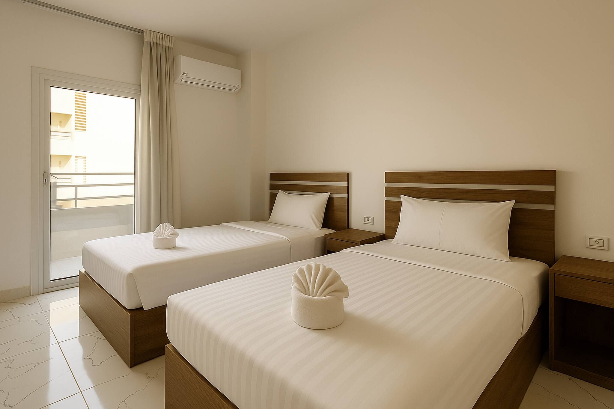 A hotel room with two beds, a sliding door to a balcony, and a ceiling-mounted air conditioning unit.