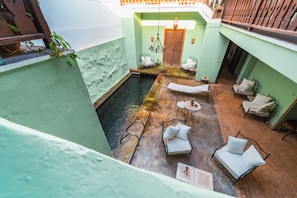 A courtyard with a pool, lounge chairs, and a door.