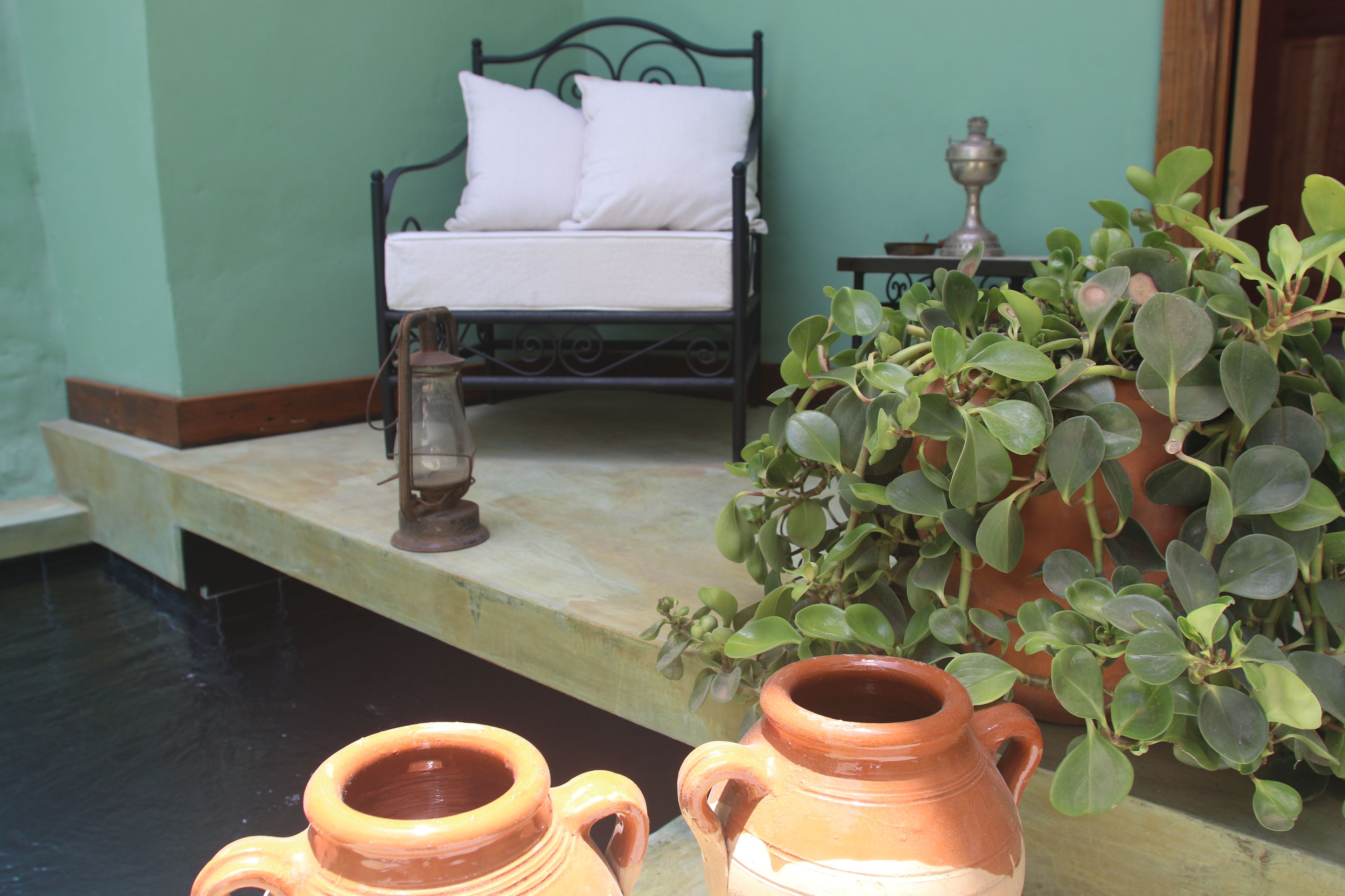 Een kamer met een bed, een kamerplant en twee terracotta potten op een tafel.