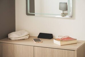 Ein Nachttisch mit Kissen, Smartphone, Buch und Lampe.