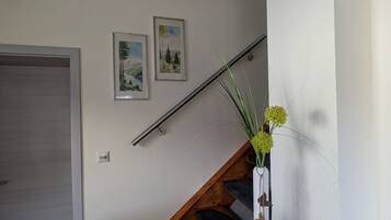 A staircase with a welcome sign, a door, and two framed pictures on the wall.