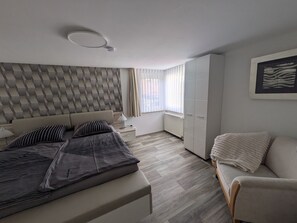 Makuuhuone, jossa on sänky, yöpöytä, lamppu, vaatekaappi ja ikkuna, jossa on verhot.