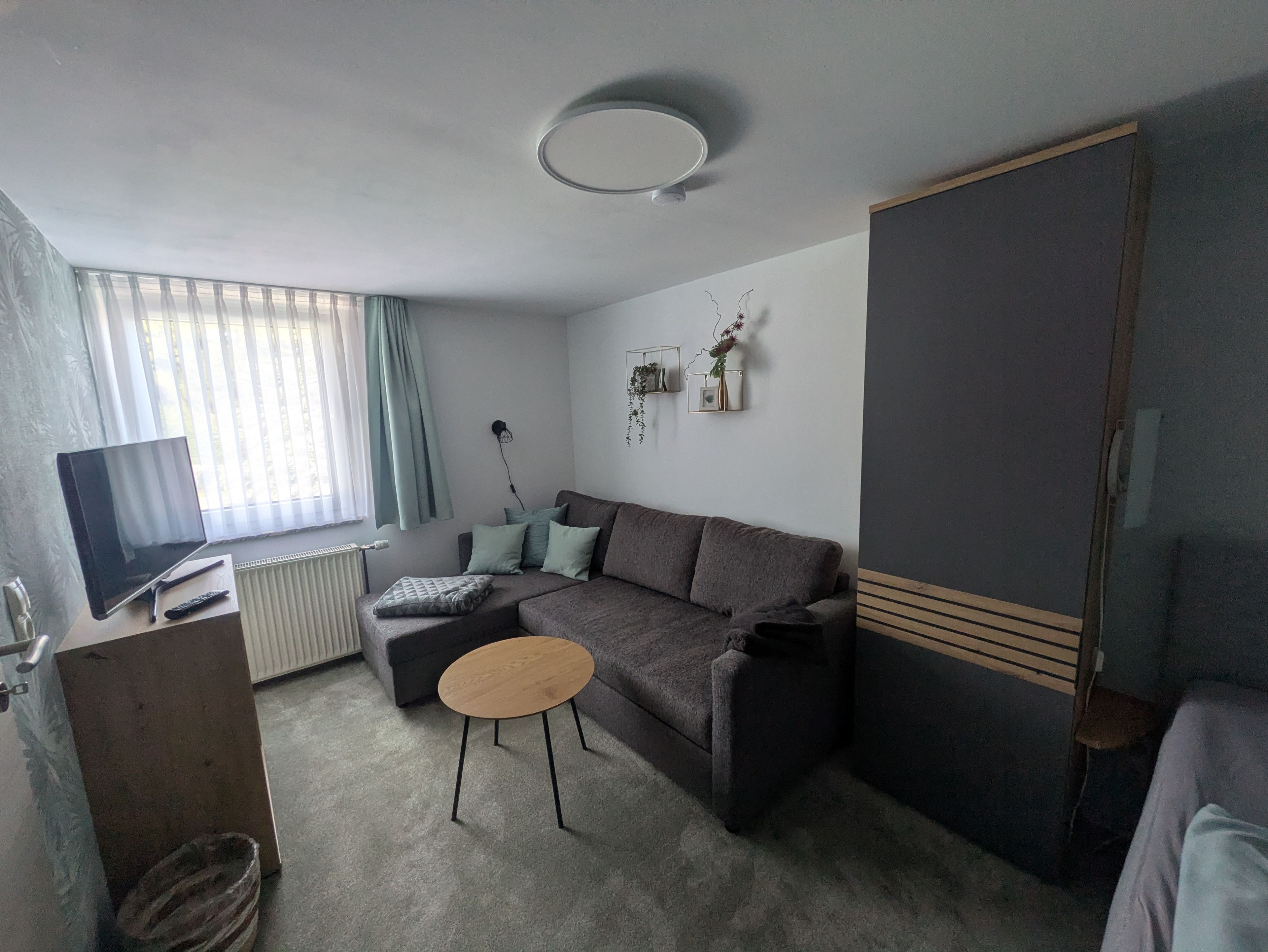 Una sala moderna con sofá, mesa de centro, televisor y radiador.