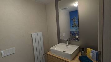 Ein Badezimmer mit weißem Waschbecken, einem Spiegel, einer Toilette, einem Handtuch und einer Duschvorhang.