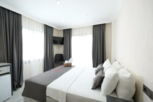 Una habitación de hotel con una cama, un escritorio y una silla.