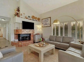 A living room with a fireplace, a sofa, a coffee table, and a wall-mounted TV. - La Quinta Resort Hideaway (La Quinta)