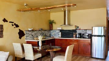 A modern kitchen with a central island, wooden cabinets, and a stainless steel refrigerator.