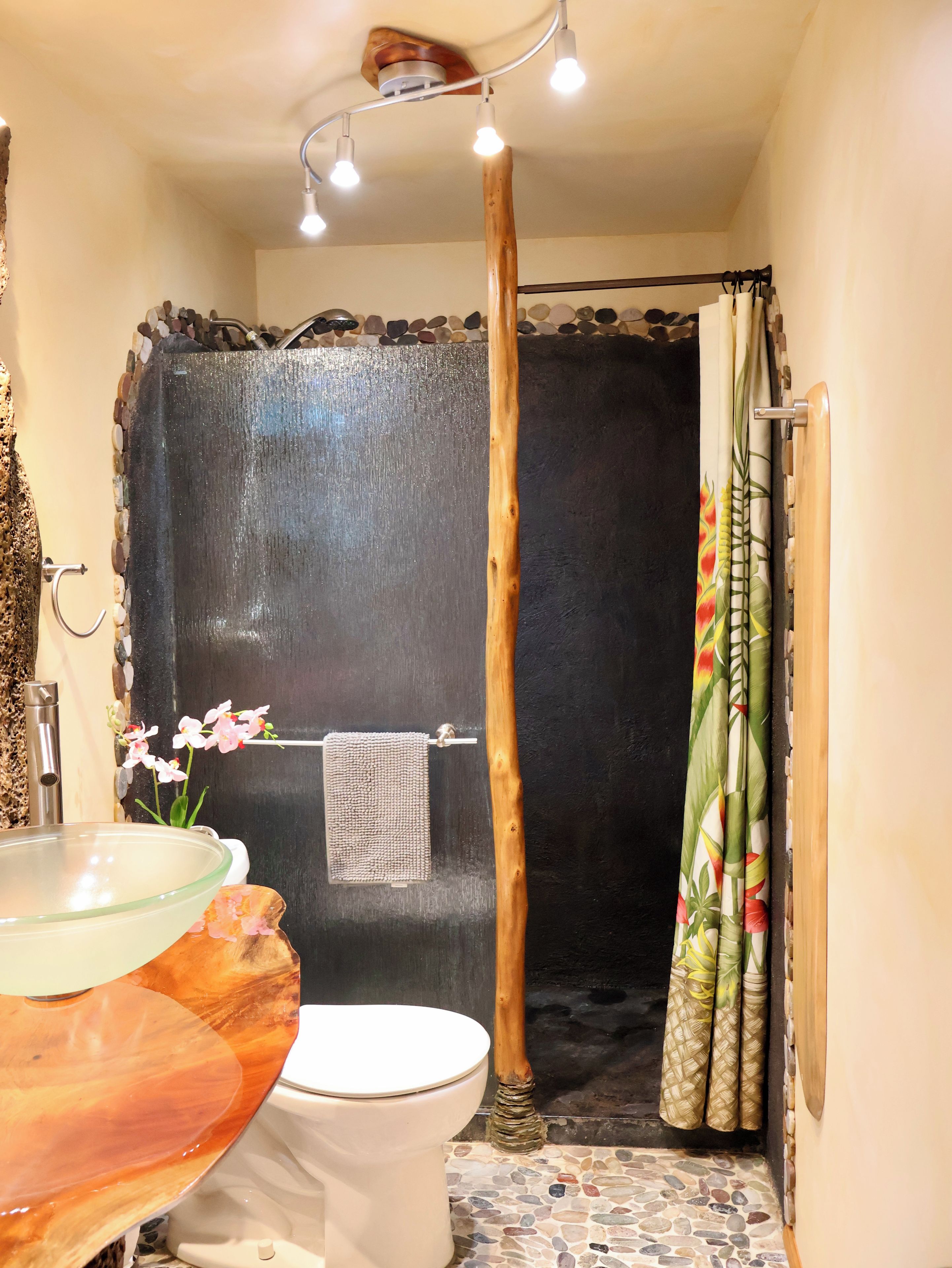 Une salle de bain avec un lavabo en verre, des toilettes blanches et un rideau de douche.
