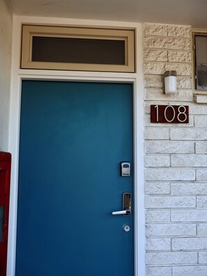 A blue door with a number plaque '108' on a white brick wall. - Cozy 1-bedroom condo in charming Paia with AC in the bedroom. (Paia)
