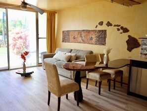 A living area with a sofa, chairs, a coffee table, and a dining table. - Cozy 1-bedroom condo in charming Paia with AC in the bedroom. (Paia)