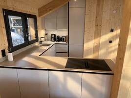 Una cocina moderna con un amplio ventanal, armarios integrados y una cocina de acero inoxidable.