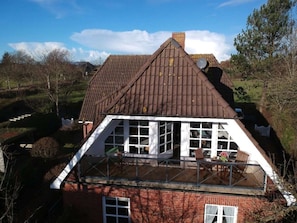 A two-story house with a sloped roof, a balcony with a railing, and a brick exterior. - Holiday Apartment in Nieblum With Balcony (Nieblum)