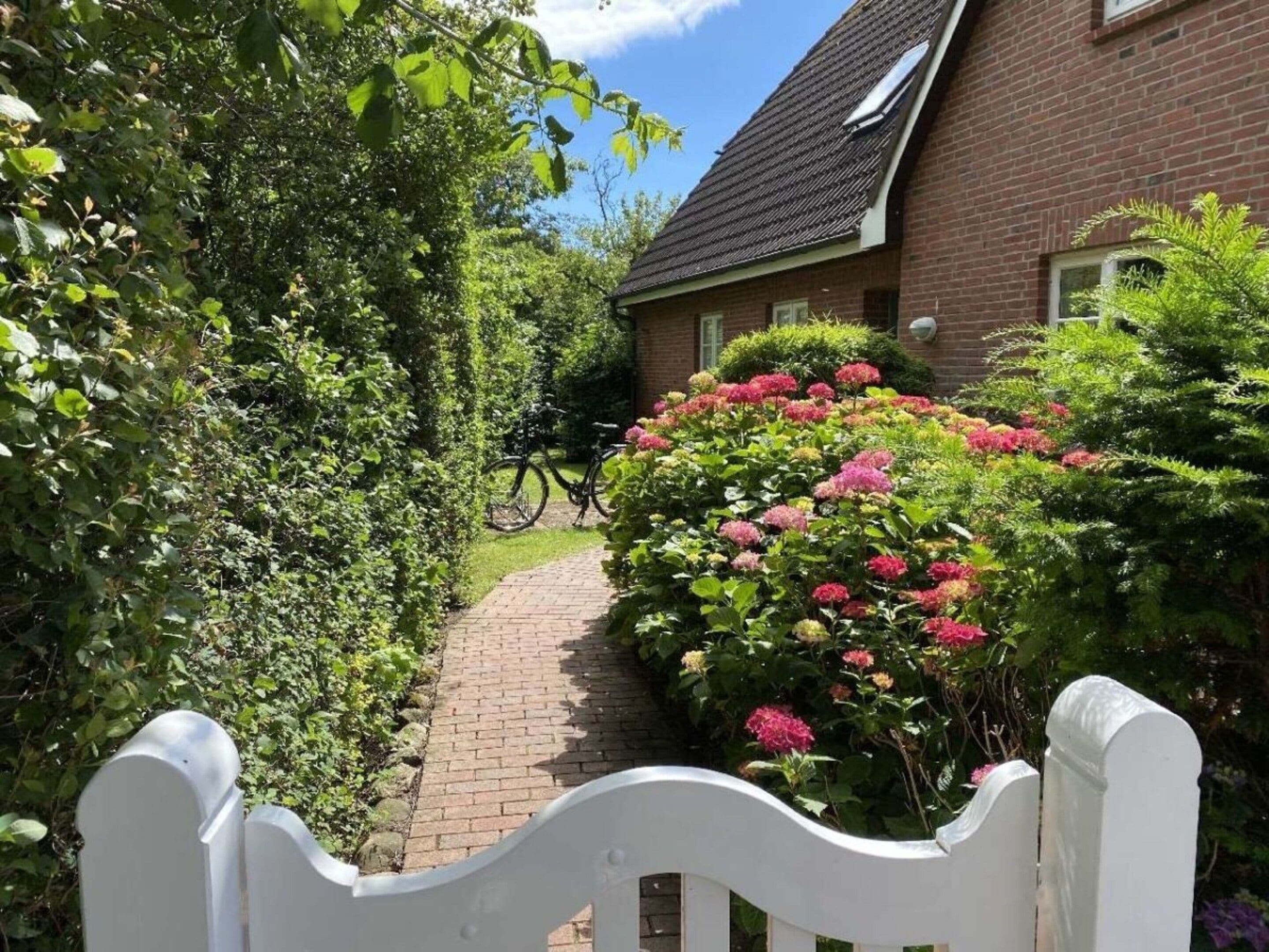 A pathway leading to a brick house with a bicycle parked nearby.