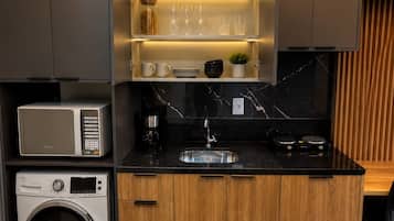 Una cocina compacta con lavadora integrada, microondas y fregadero.