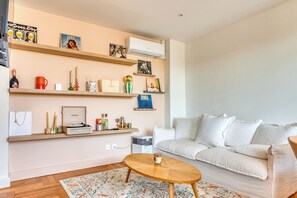 A living room with a sofa, coffee table, and shelves with various items. - Le Minéral - Métro C - Caluire proche hôpital Croix Rousse - Climatisé (Caluire-et-Cuire)