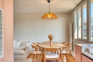 A dining area with a round wooden table, six chairs, a hanging light fixture, and a vase with dried flowers. - Le Minéral - Métro C - Caluire proche hôpital Croix Rousse - Climatisé (Caluire-et-Cuire)