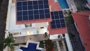 An aerial view of a residential area with solar panels on the roofs, a swimming pool, and a small garden area.