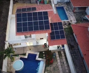 An aerial view of a residential area with solar panels on the roofs, a swimming pool, and a small garden area. - Casa de Hospedagem Duplex Linda na Praia do Meio/Araçagy98.9.8.8.3.7-9.4.6.0 (São José de Ribamar)
