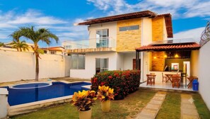 A two-story house with a swimming pool, a patio with outdoor furniture, and a small garden with colorful flowers. - Casa de Hospedagem Duplex Linda na Praia do Meio/Araçagy98.9.8.8.3.7-9.4.6.0 (São José de Ribamar)