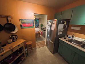 Eine kompakte Küche mit Kühlschrank, Spüle und einem Essbereich mit Tisch und Stühlen.