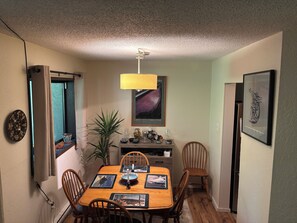 Ein Essbereich mit einem Holztisch, Stühlen, einer Chandelierleuchtre und Kunstwerken an den Wänden.