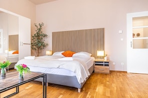 A modern bedroom with a bed, bedside tables, a mirror, and a wooden floor. - Your Vienna City Break Stylish 2BR (Vienna)