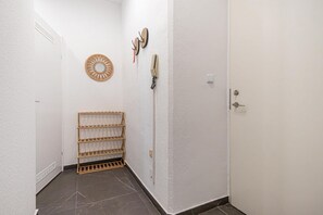 A narrow hallway with a wooden drying rack, a wall-mounted telephone, and a door with a keyhole. - Your Vienna City Break Stylish 2BR (Vienna)