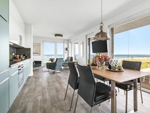 A modern kitchen with a dining area, large windows, and a view of the beach. - Apartment in Kappeln With Swimming Pool (Kappeln)