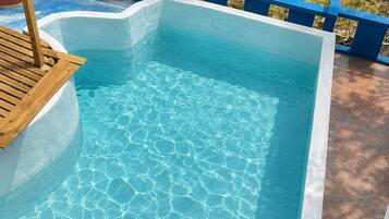 Ein rechteckiger Swimmingpool mit klarem, blauem Wasser, umgeben von einem blau-weißen Fliesensteg.