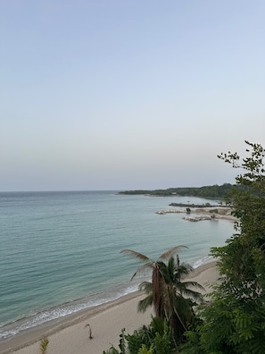 Ein Strand mit klarem Wasser, sandigem Ufer und etwas Vegetation.