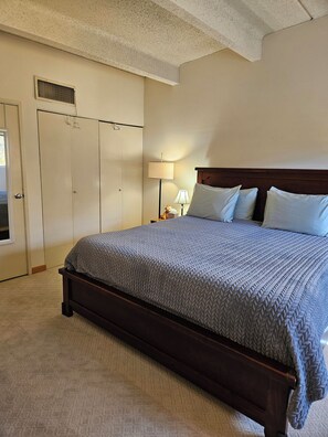 A bedroom with a large bed, a nightstand, a lamp, a wardrobe, and a vent on the ceiling. - SHE306 Fabulous 1 bedroom + loft by the Super Bee Lift, makes a vacation perfect (Frisco)