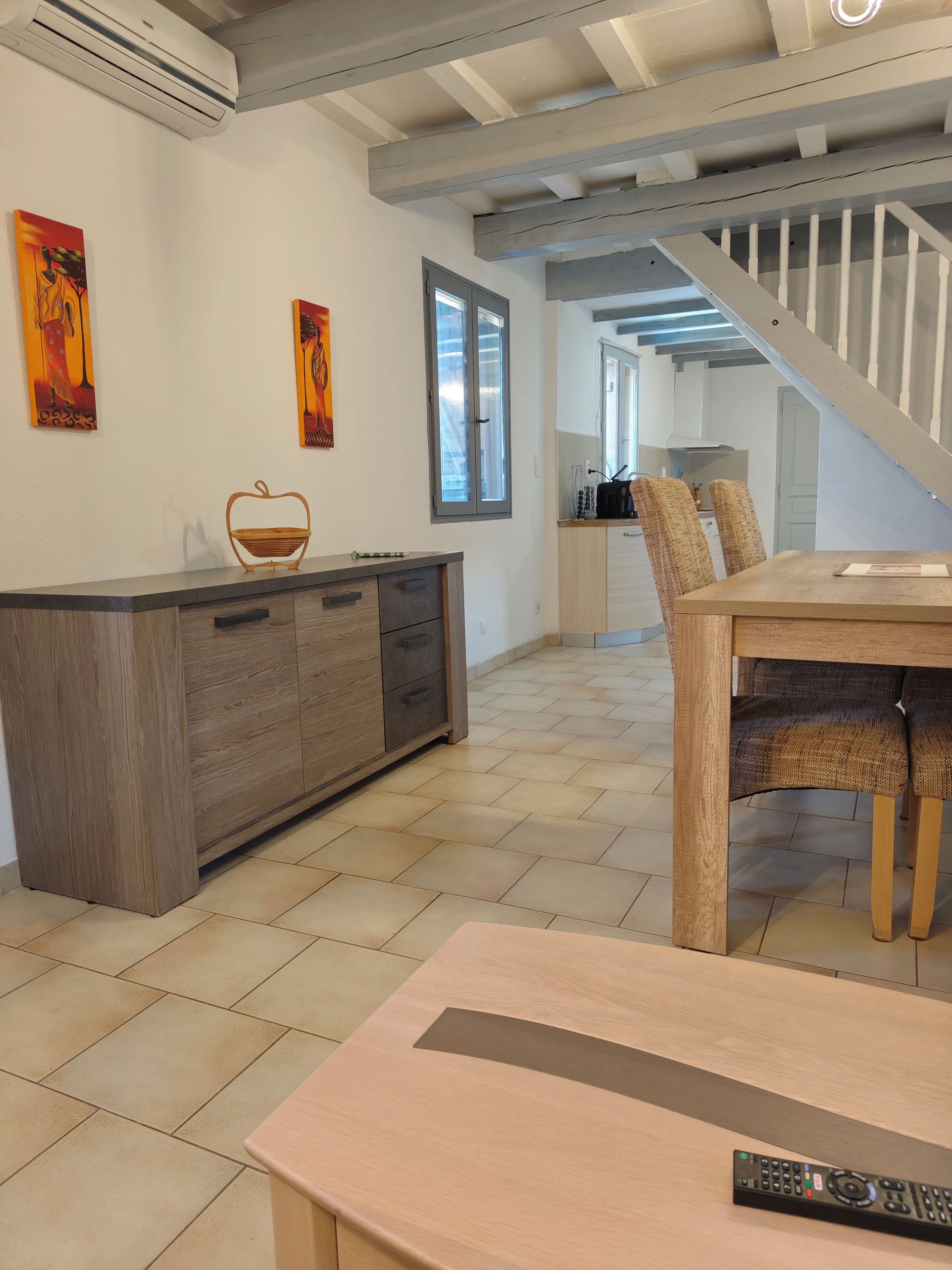 Eine moderne Küche mit einer Holzinsel, ein Essbereich mit Korbstühlen und eine Treppe, die eine weitere Ebene hinaufführt.