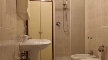 A bathroom with a sink, toilet, bidet, and a shower enclosure.