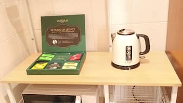 A kitchen area with a microwave, a kettle, a tea caddy, and a framed certificate on the counter.