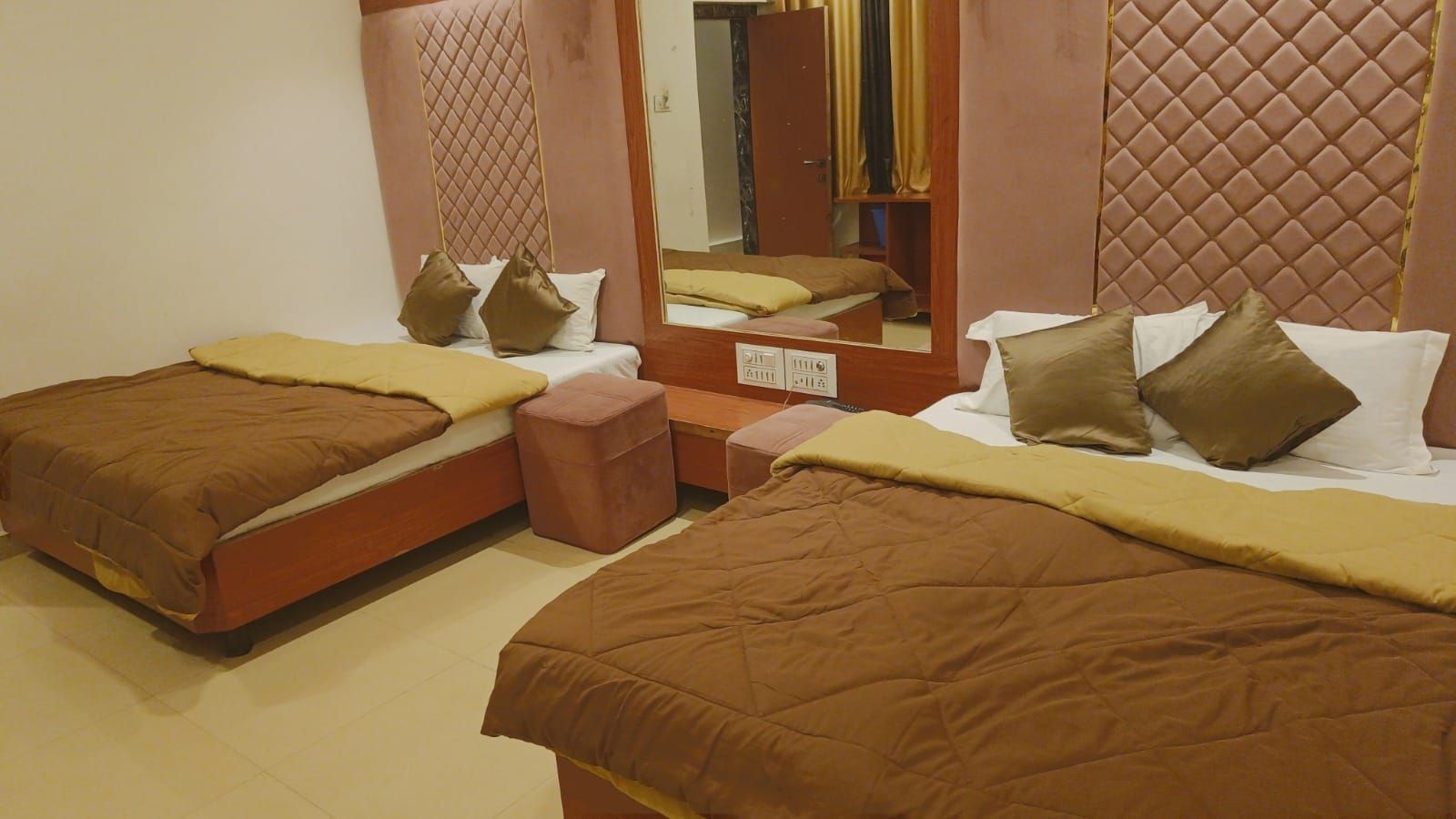 Una habitación de hotel con dos camas, un espejo y un armario.