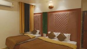 A hotel room with two beds, a wall-mounted air conditioner, and a wall-mounted light fixture. - Hotel Dwarka Bhavan (Shirdi)
