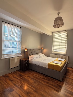 Ein Schlafzimmer mit einem großen Bett, zwei Nachttischen, einer Heizung und einer Hängeleuchte.