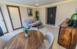 A modern living room with a round wooden table, white chairs, a sofa, and a potted plant. - Casa Blanche | Central Location + Parking (Oaxaca de Juárez)