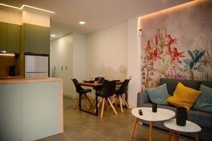 A modern living room with a dining area, a sofa with cushions, and a wall with a floral mural. - Spherae Nebula (El Cotillo)