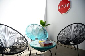 A room with two black wireframe chairs, one with a glass seat, and a red stop sign on the wall. - Spherae Nebula (El Cotillo)