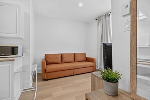 Ein modernes Wohnzimmer mit einer Couch, einer Mikrowelle, einer Topfpflanze und einem Holztisch.