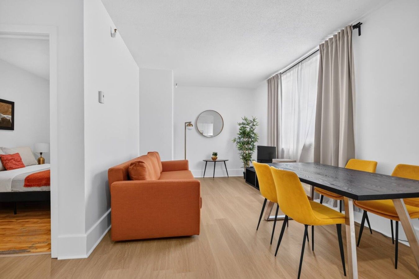Un salon moderne comprenant un canapé, une table à manger, des chaises et une petite table d’appoint.