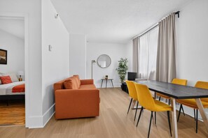 Una sala moderna con sofá, mesa de comedor, sillas y una mesita auxiliar.