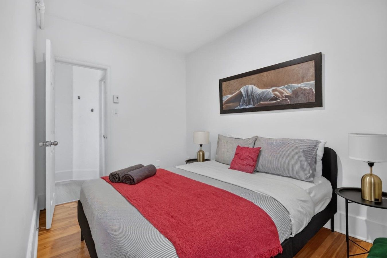 Un dormitorio con cama, un cuadro, una mesita de noche y una lámpara.