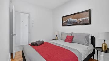 Un dormitorio con cama, un cuadro, una mesita de noche y una lámpara.