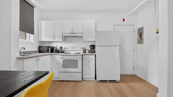Una cocina compacta con armarios blancos, estufa, microondas y refrigerador.